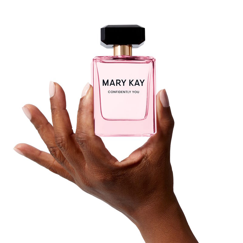 The light pink Mary Kay Confidently You bottle is held heroically by a hand
