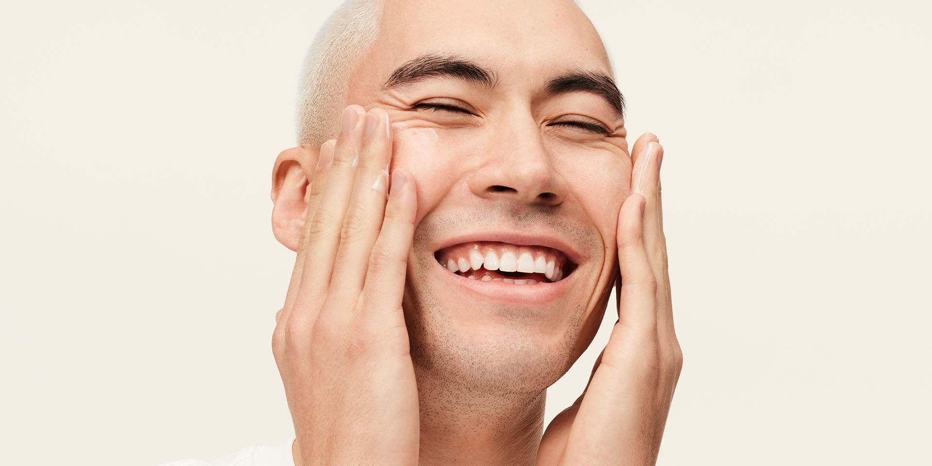 Modelo masculino sonriendo mientras aplica la Hidratante Avanzada MKMen&reg; en el rostro