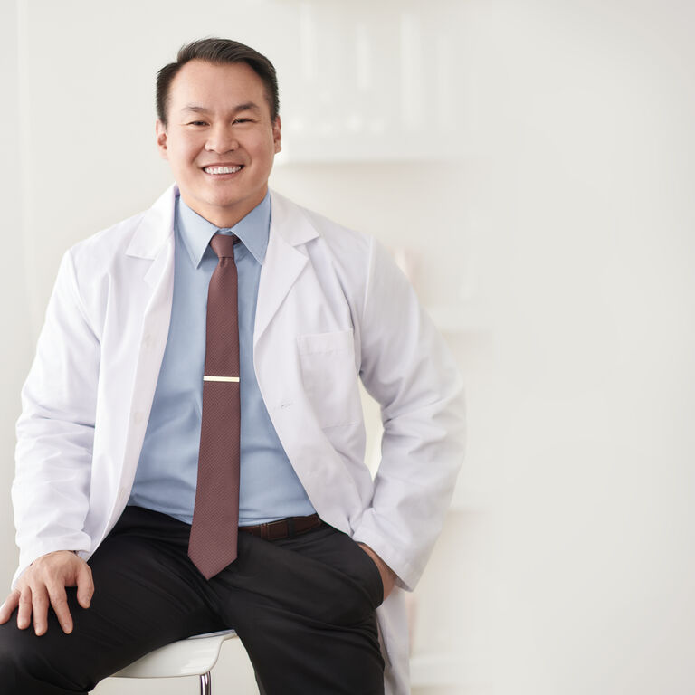David Gan, Senior Manager of Upstream Research, Clinical Research, & Scientific Credentialing at Mary Kay, is wearing a white lab coat and smiling at the camera.