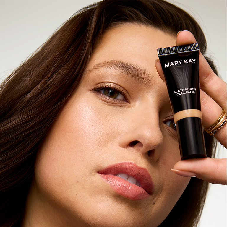 Woman holding Mary Kay Multi-Benefit concealer tube to her face